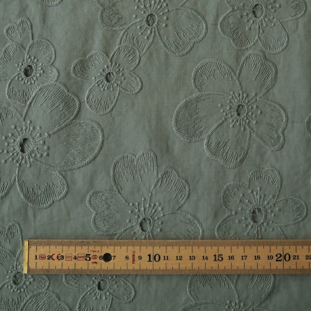 Sage green embroidered cotton dressmaking fabric with floral pattern