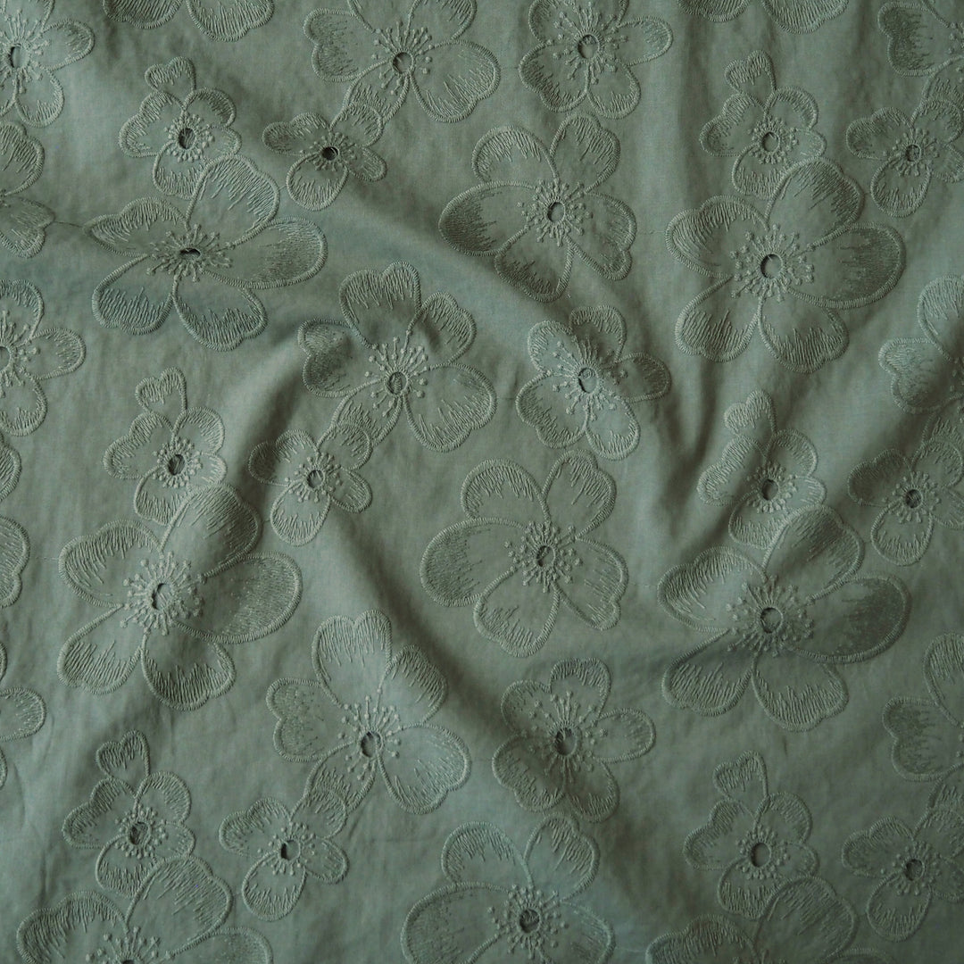 Sage green embroidered cotton dressmaking fabric with floral pattern