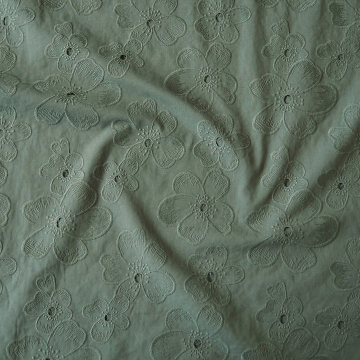 Sage green embroidered cotton dressmaking fabric with floral pattern