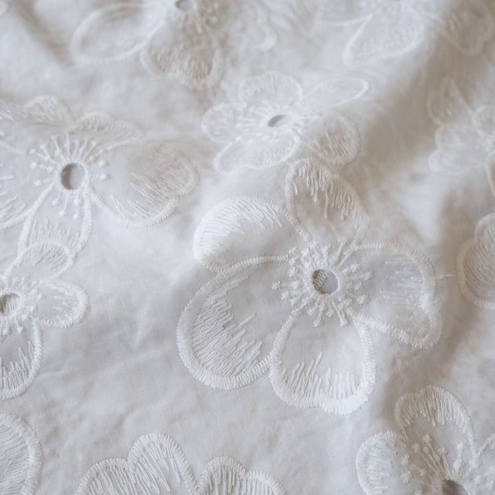 White embroidered cotton dressmaking fabric with floral pattern