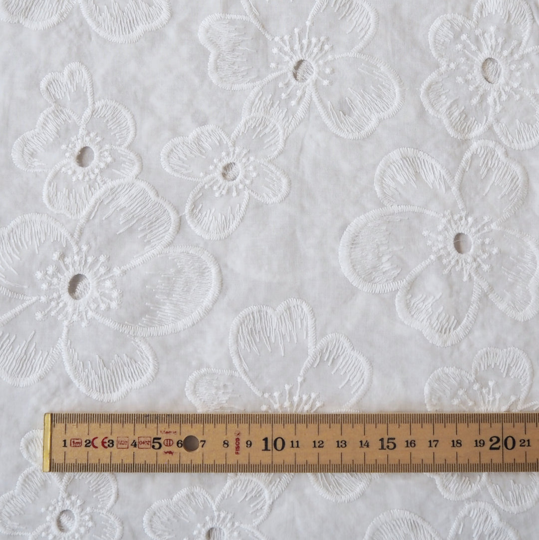White embroidered cotton dressmaking fabric with floral pattern
