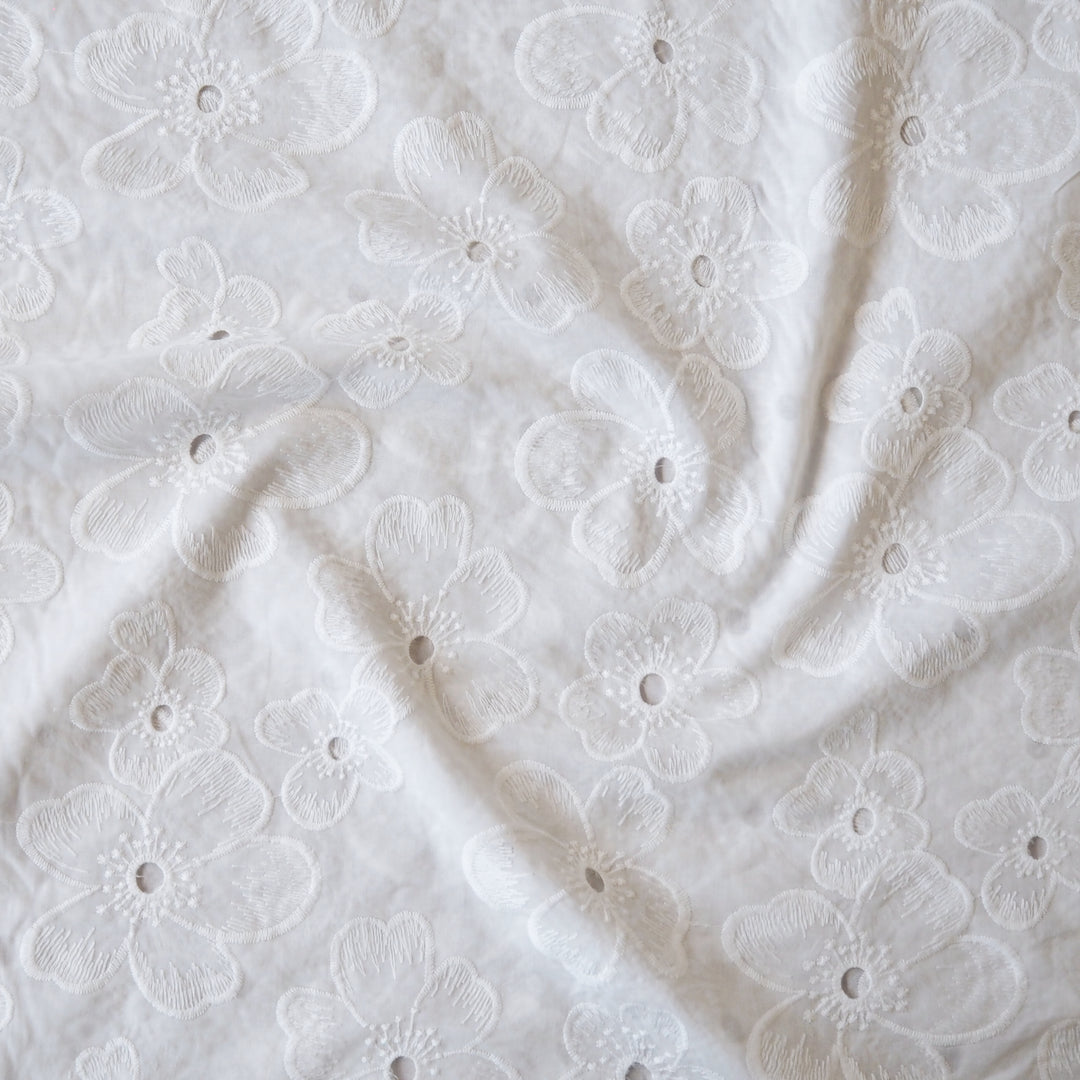 White embroidered cotton dressmaking fabric with floral pattern