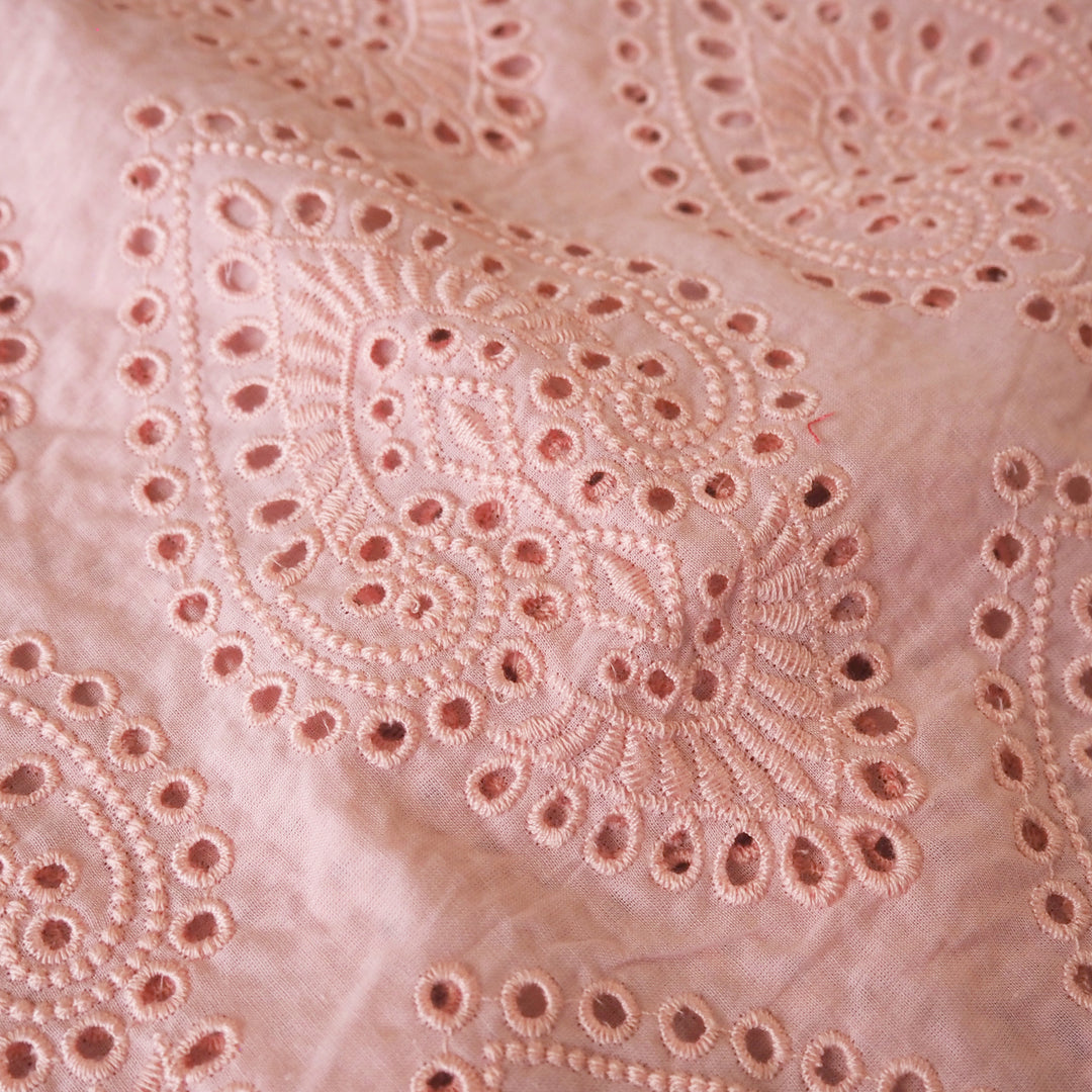 Peachy pink embroidered cupro dressmaking fabric with geometric eyelet pattern