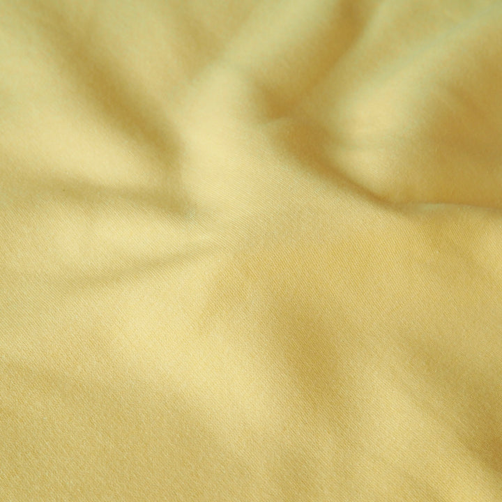 Buttercream yellow fleeceback organic cotton sweatshirting fabric, cosy and stretchy for sweatshirts and joggers.