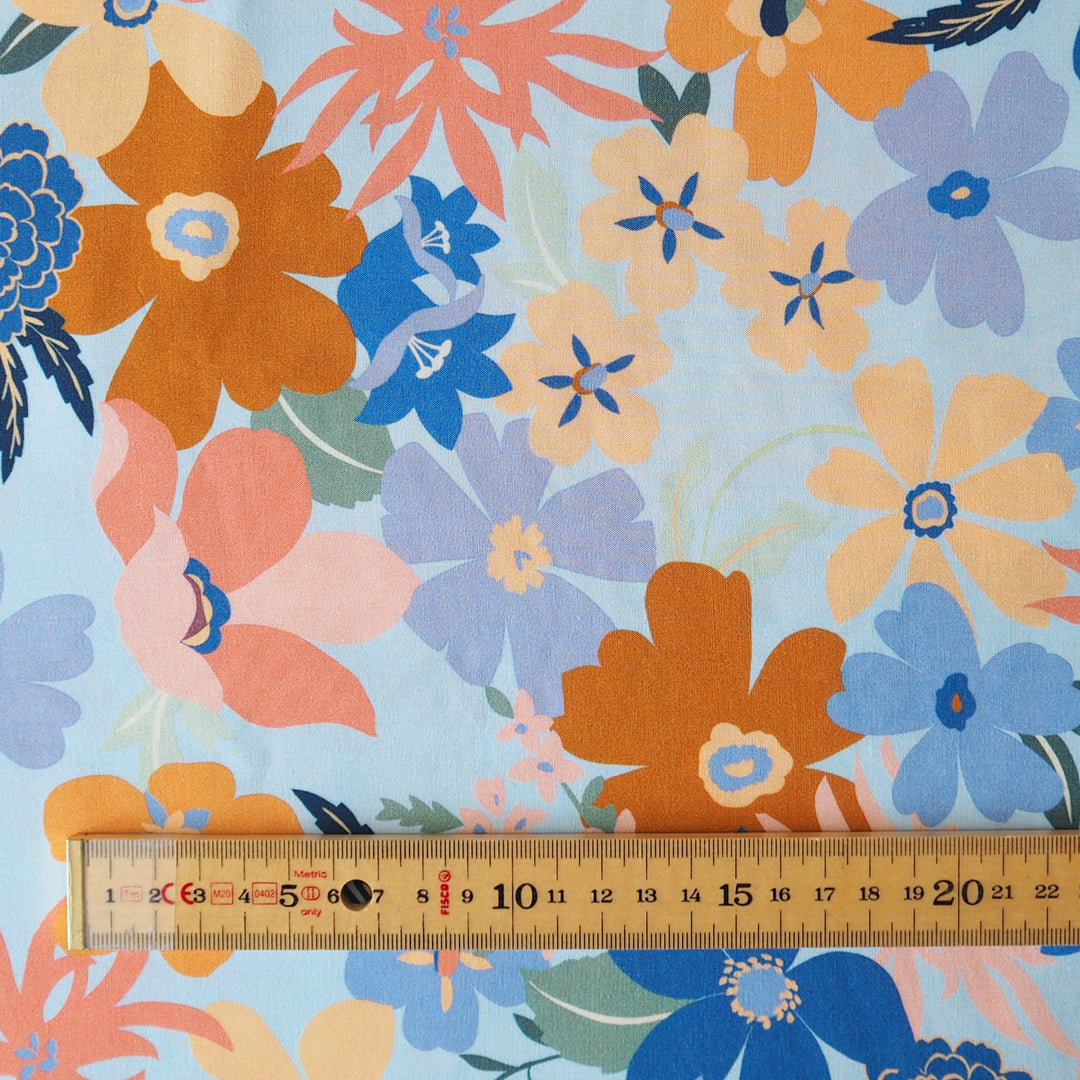 Floral fabric pattern with a ruler at the bottom for scale on a light blue background