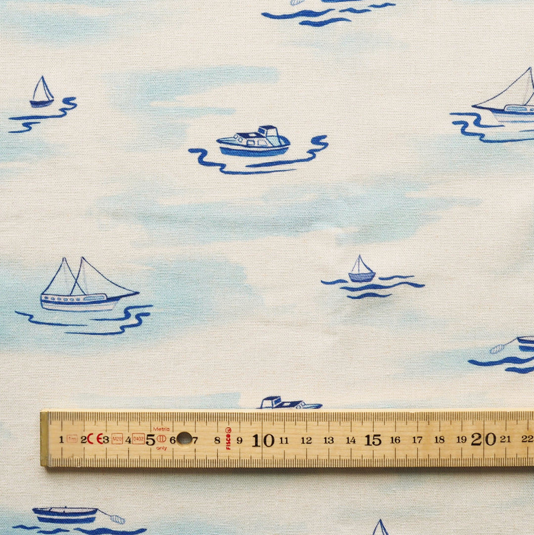 Fabric with blue boat patterns on a white background, ruler for scale.