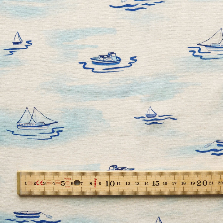 Fabric with blue boat patterns on a white background, ruler for scale.