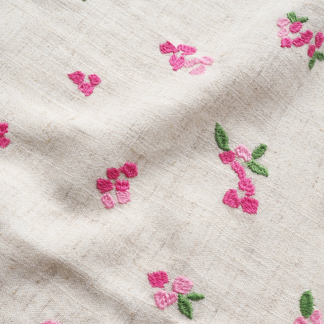 Close-up of beige fabric with pink floral embroidery
