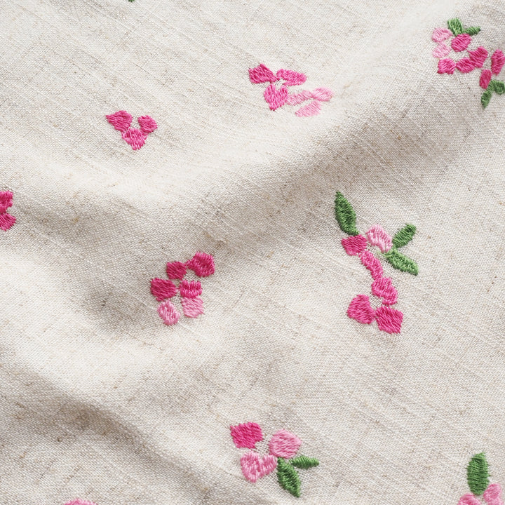Close-up of beige fabric with pink floral embroidery