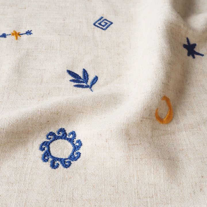 Close-up of embroidered patterns on a beige fabric background