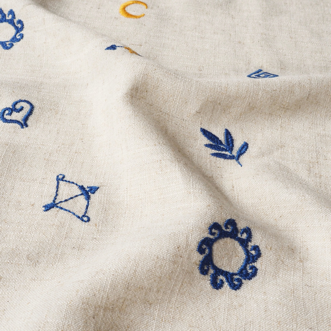 Close-up of beige fabric with embroidered blue designs.