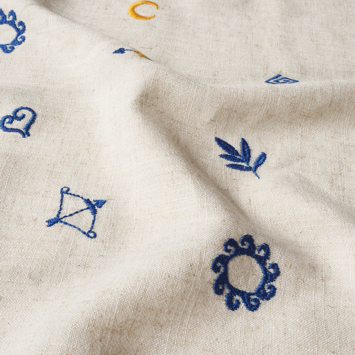 Close-up of beige fabric with embroidered blue designs.