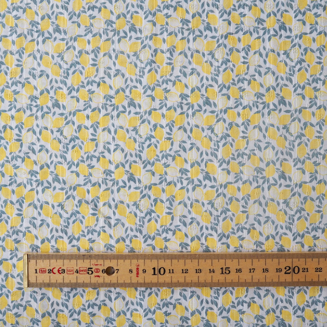 Fabric with yellow lemon pattern and a ruler at the bottom for scale.
