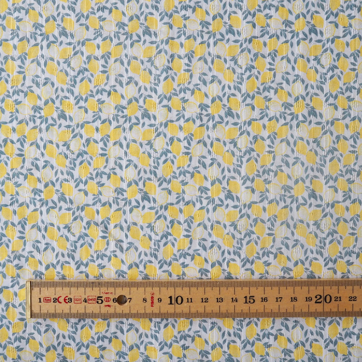 Fabric with yellow lemon pattern and a ruler at the bottom for scale.