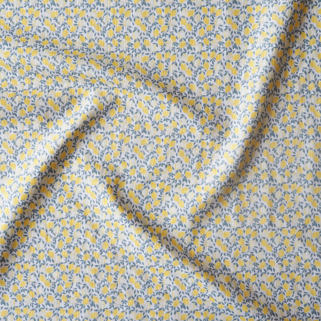 Floral patterned fabric with yellow lemons on a light background