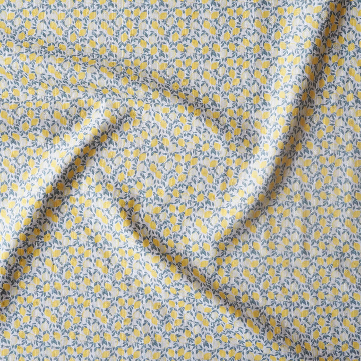 Floral patterned fabric with yellow lemons on a light background