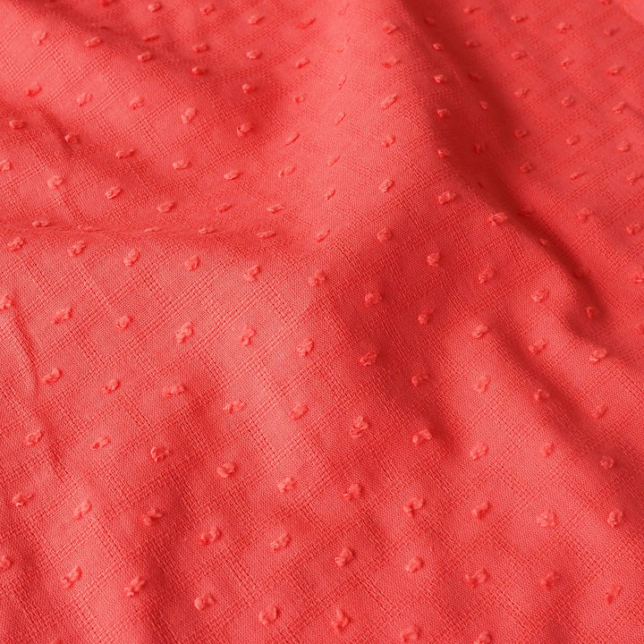 Close-up of textured coral fabric with a subtle pattern