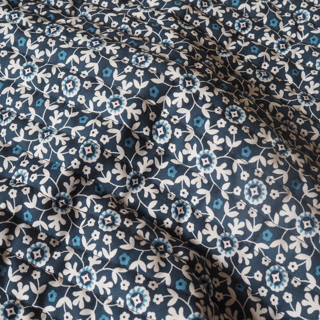 Floral patterned fabric with blue and white flowers on a dark blue background