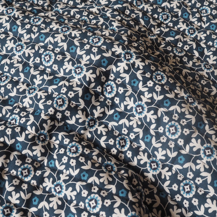 Floral patterned fabric with blue and white flowers on a dark blue background