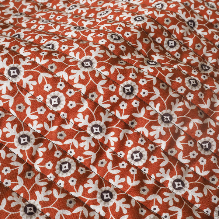 Close-up of a floral patterned fabric with red, white, and brown colors.