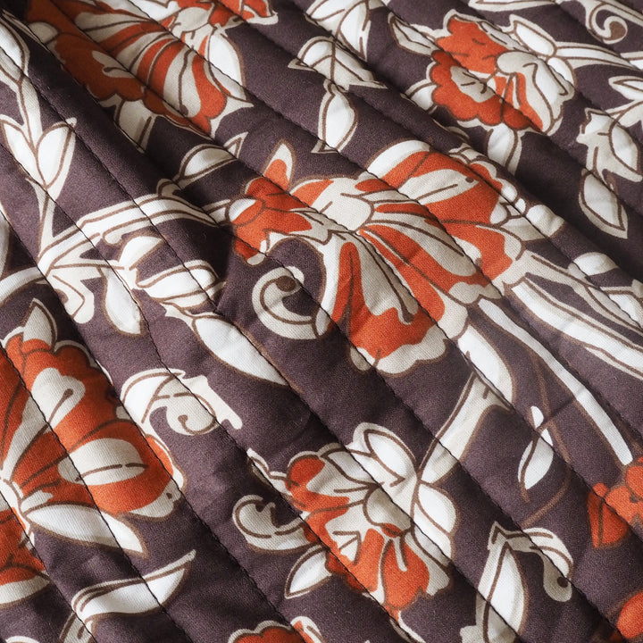 Close-up of fabric with a floral pattern featuring rust, white, and brown colours.