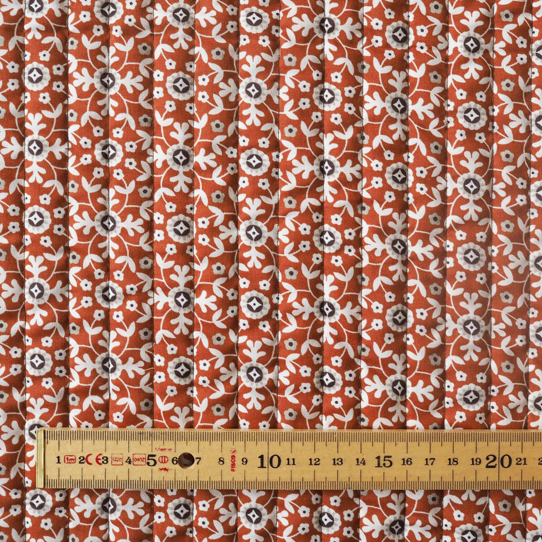 Fabric with a floral pattern and a ruler for scale on a white background