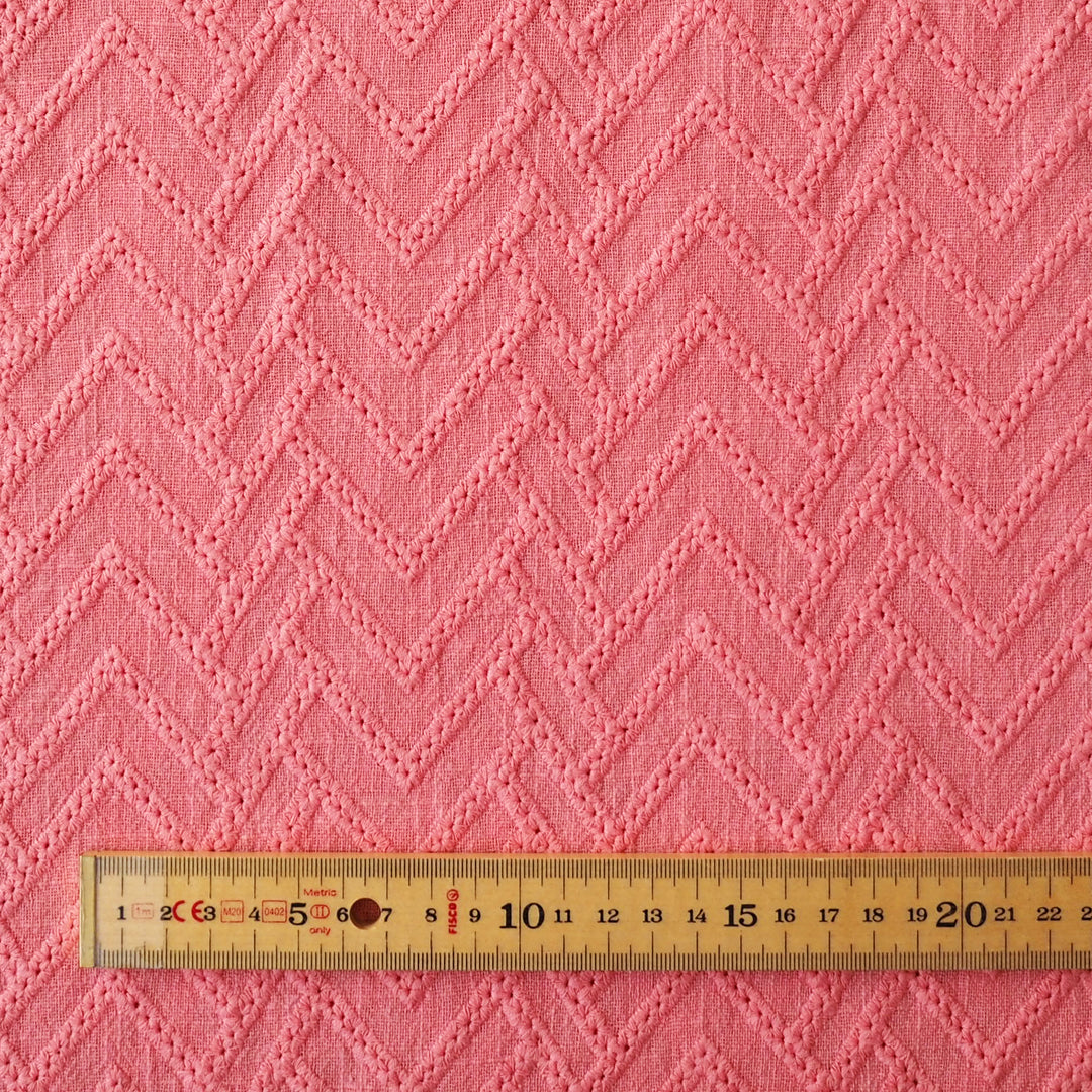 Pink fabric with a zigzag pattern and a wooden ruler at the bottom for scale.