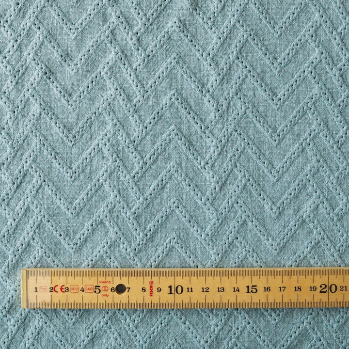 Textured blue fabric with a wooden ruler for scale