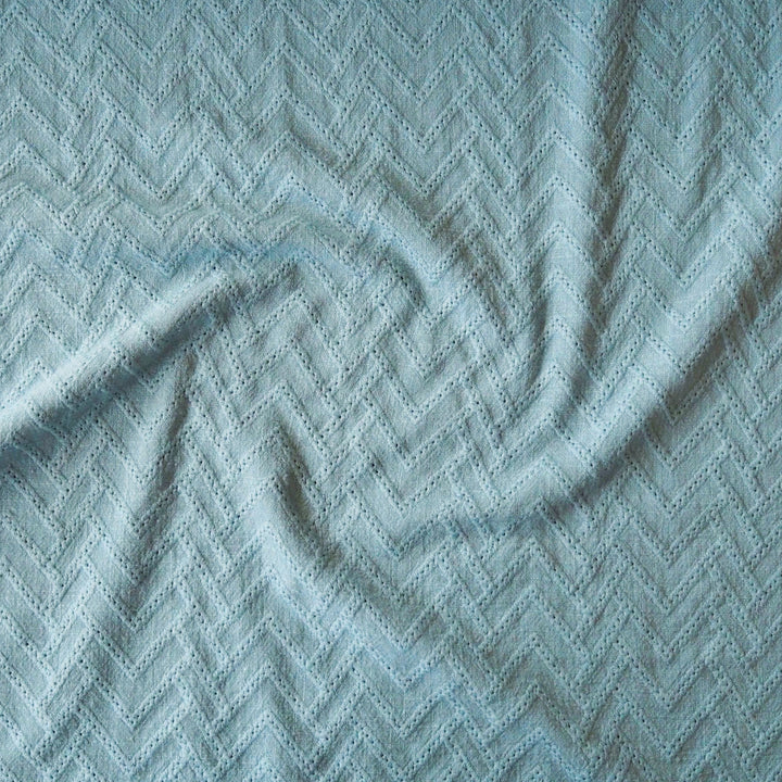 Textured fabric with a zigzag pattern in a light blue color.