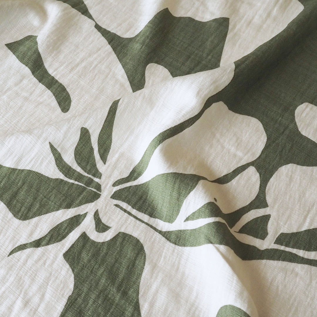 Close-up of a green leaf pattern on a white fabric surface