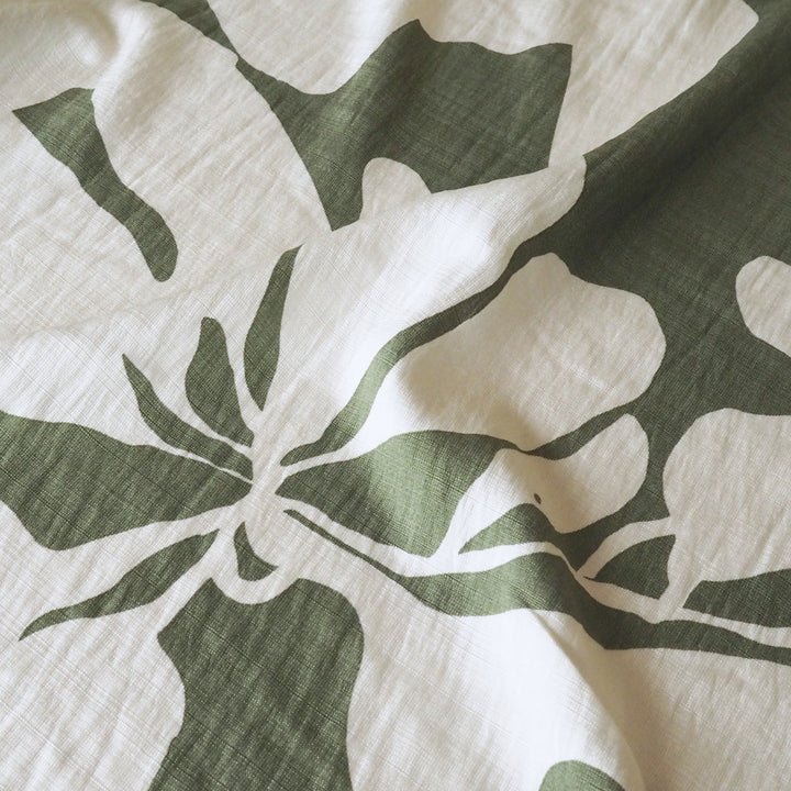 Close-up of a green leaf pattern on a white fabric surface