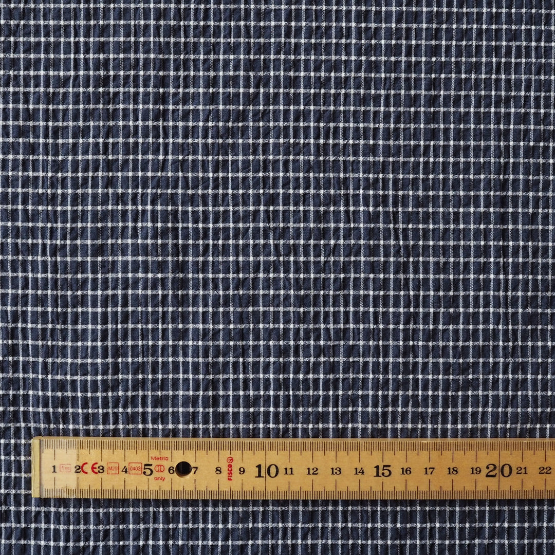 Navy checkered fabric with a wooden ruler at the bottom for scale.