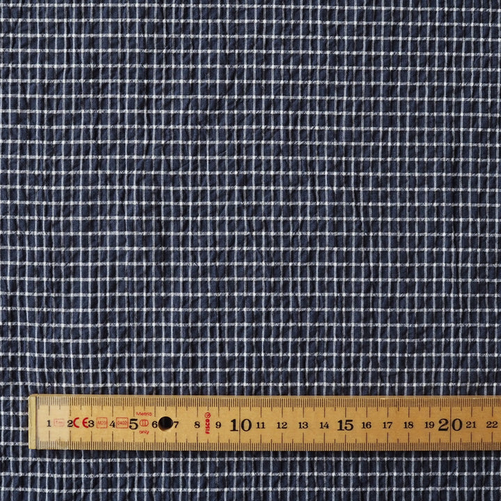 Navy checkered fabric with a wooden ruler at the bottom for scale.