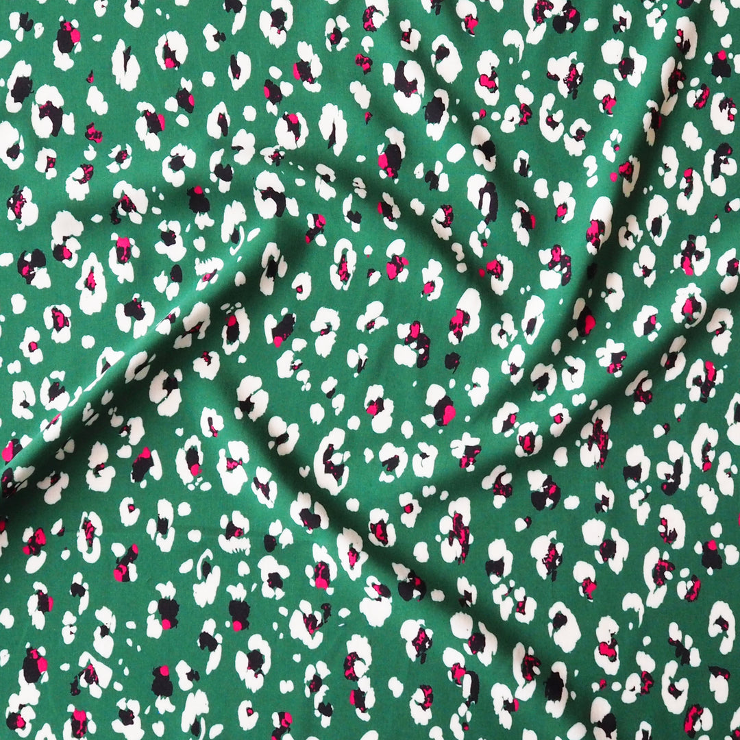 Fabric with an abstract floral print pattern on a green background