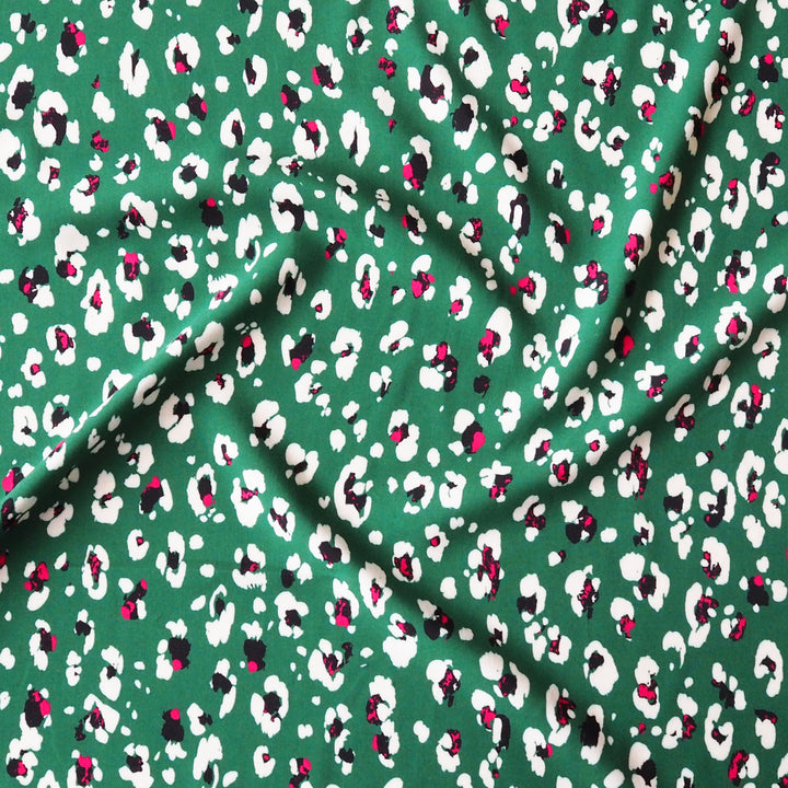 Fabric with an abstract floral print pattern on a green background