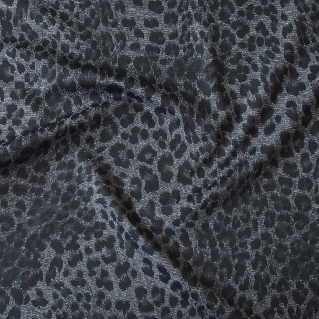Leopard print fabric with black spots on a gray background