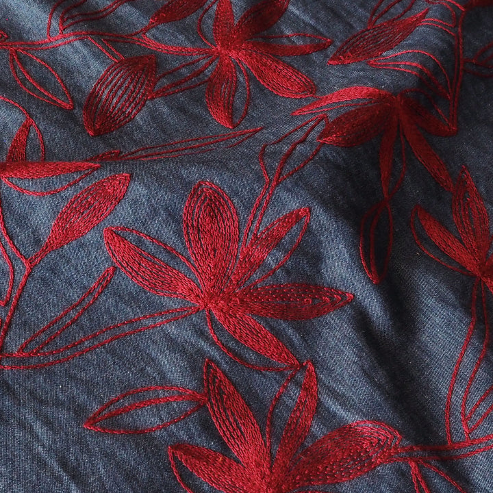 A close-up of dark gray fabric with red floral embroidery.