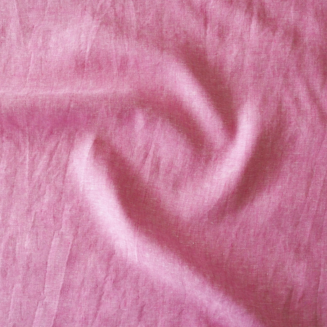 A close-up of pink fabric with a soft, slightly sheer texture and gentle folds.
