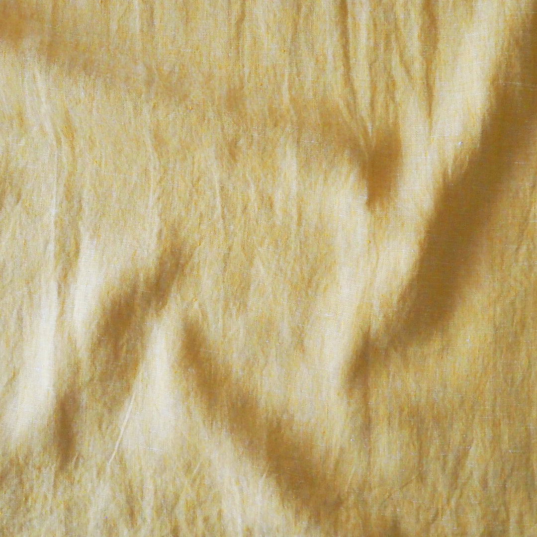 A close-up texture shot of a soft fabric in a warm yellow colour, showing the fuzzy pile and subtle shadows.