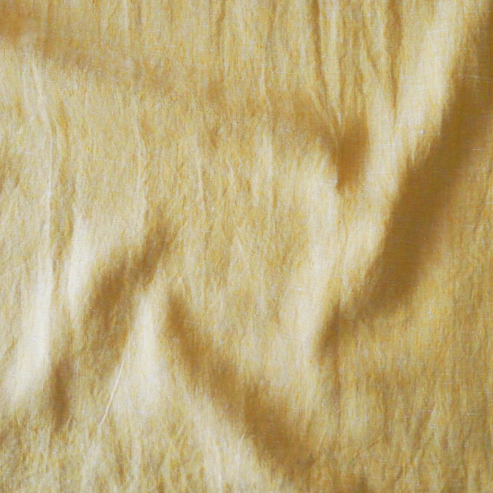 A close-up texture shot of a soft fabric in a warm yellow colour, showing the fuzzy pile and subtle shadows.