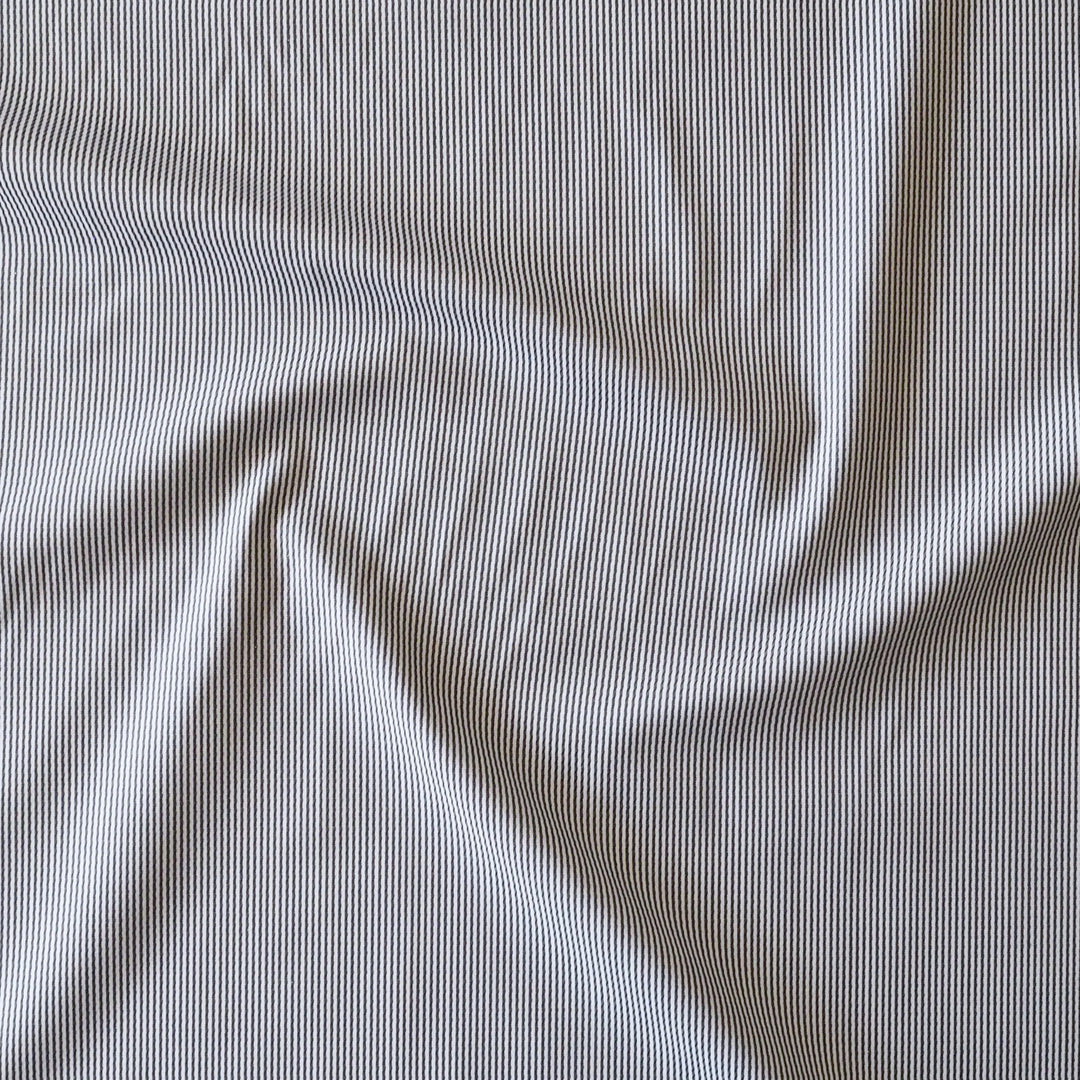 A close-up of draped fabric with a fine vertical stripe pattern in navy and off-white.