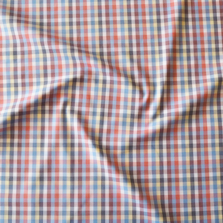 A close-up of draped plaid fabric with a multicolor checkered pattern featuring red, blue, yellow, white, and dark gray lines.