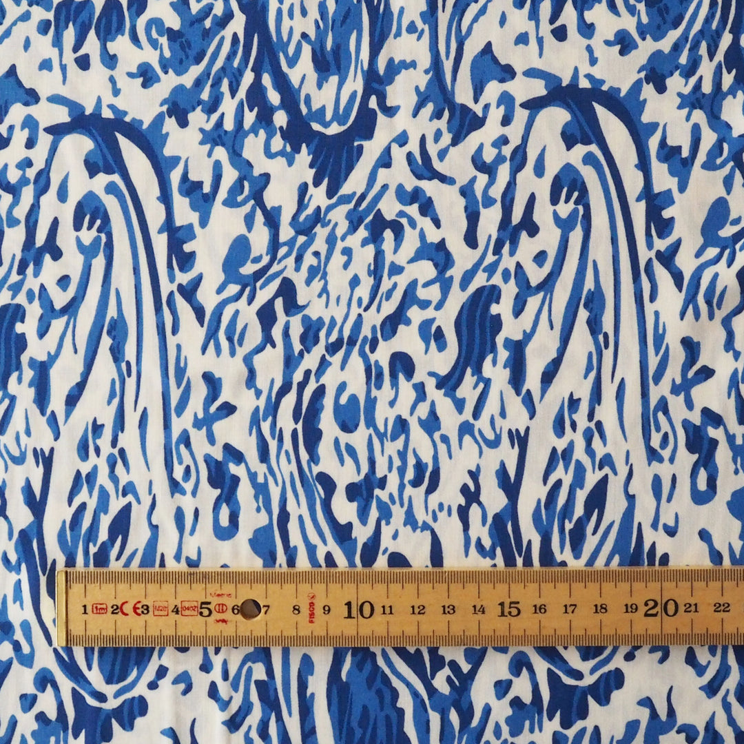 Blue and white patterned fabric with a wooden ruler showing centimeter measurements along the bottom edge.