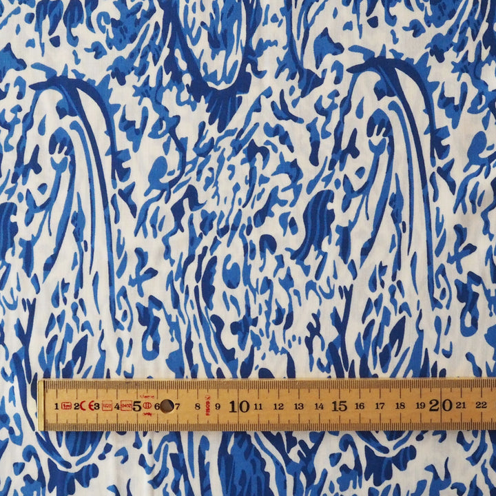 Blue and white patterned fabric with a wooden ruler showing centimeter measurements along the bottom edge.
