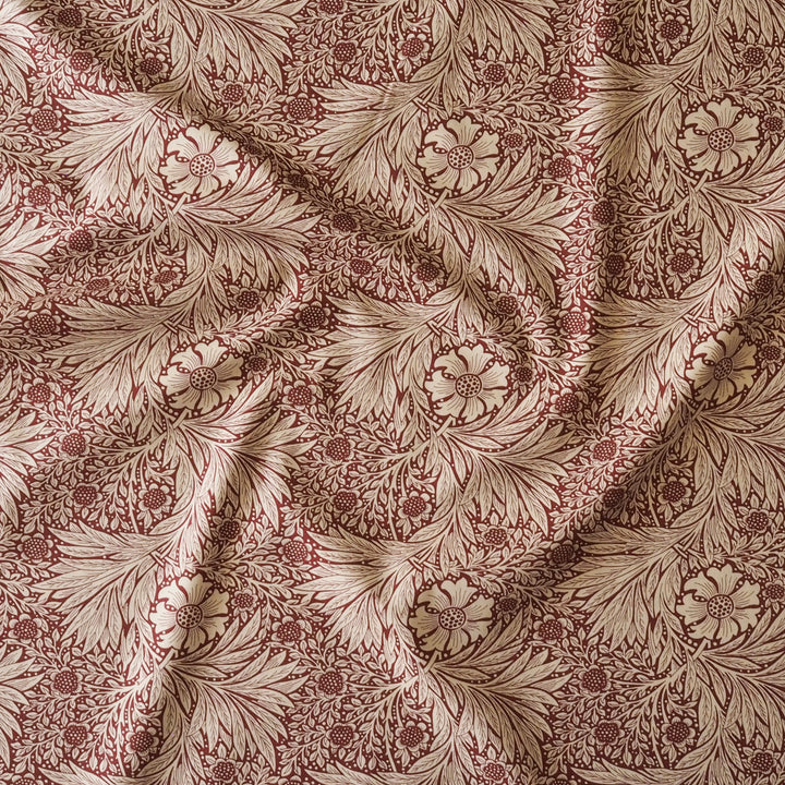 A close-up of draped fabric with an all-over floral and leaf pattern in deep red and warm beige.
