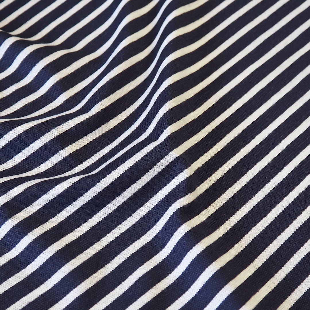 A close-up of a striped fabric with alternating navy blue and off-white diagonal stripes, showing a soft woven texture and gentle folds.