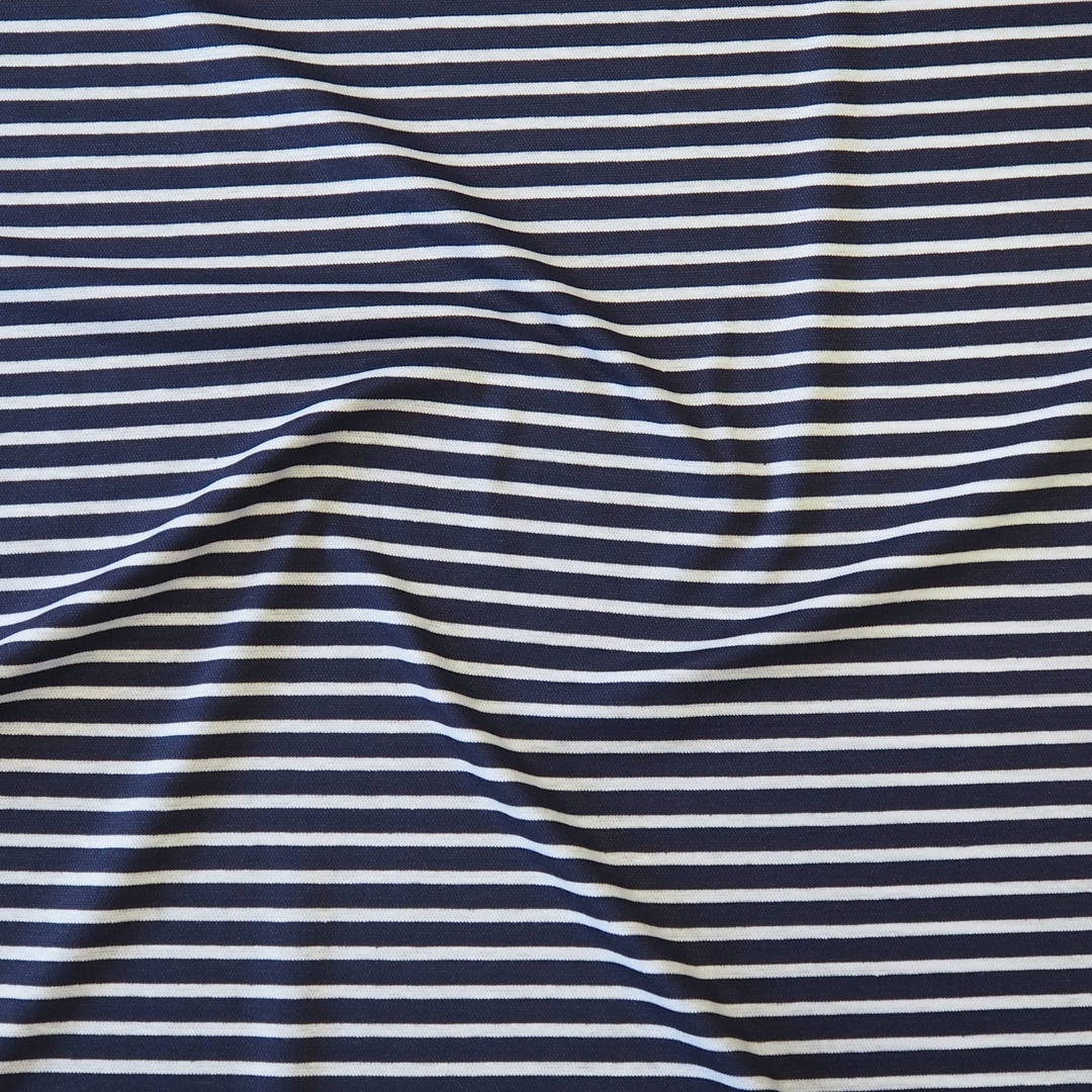 A close-up of a striped fabric with alternating navy blue and off-white horizontal stripes, shown with soft folds and wrinkles.