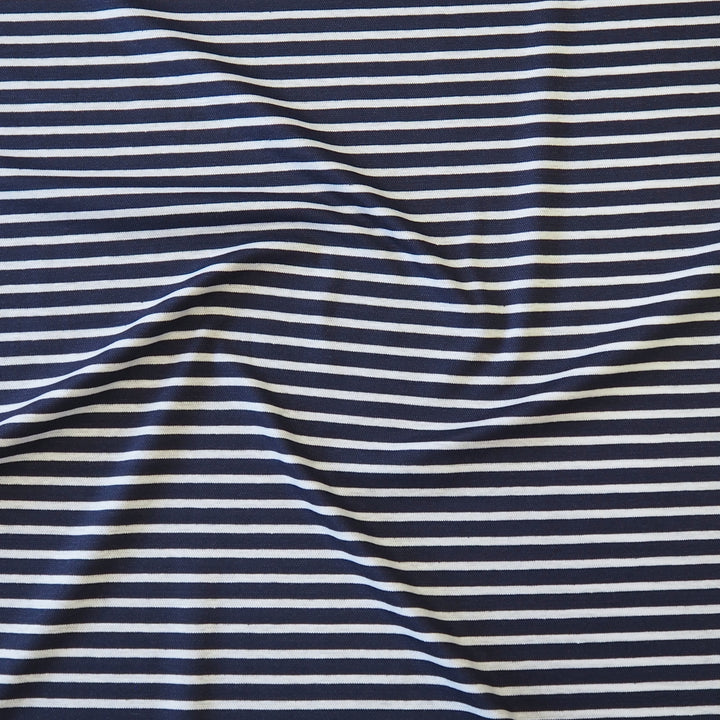 A close-up of a striped fabric with alternating navy blue and off-white horizontal stripes, shown with soft folds and wrinkles.