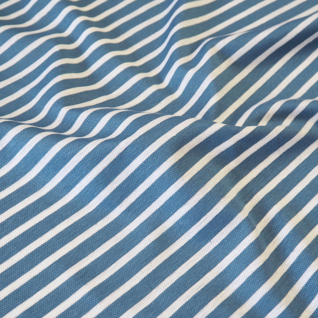 A close-up of blue and white striped fabric with a woven texture, shown with soft folds and shadows.