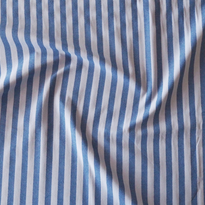 Blue vertically striped fabric with a soft, draped texture.